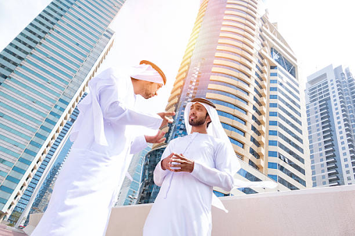 Two men in traditional attire discuss business against the backdrop of modern skyscrapers in IFZA Free Zone.